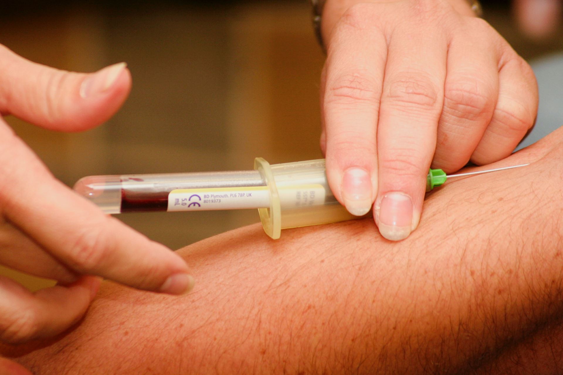 a health care assistance taking a vial of blood