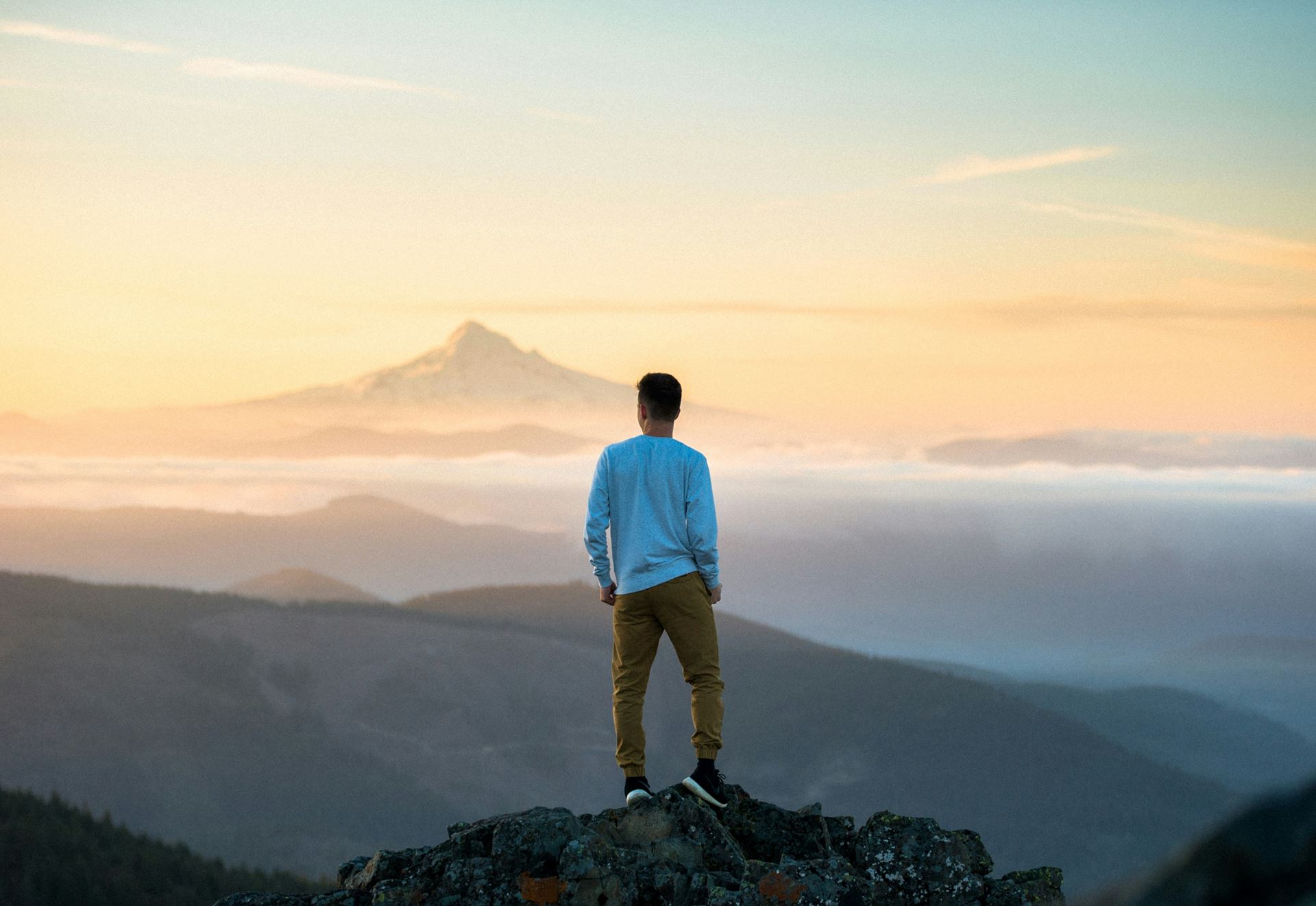a man stood looking out on a mountain scene, his back is to the camera