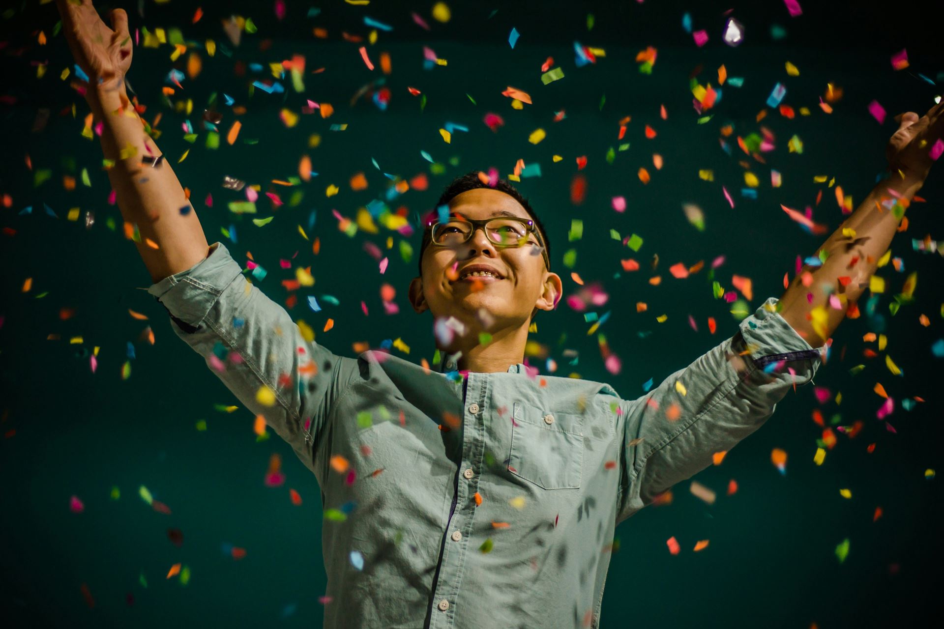 a man with the arms in the air as if celebrating, confetti is raining down on him