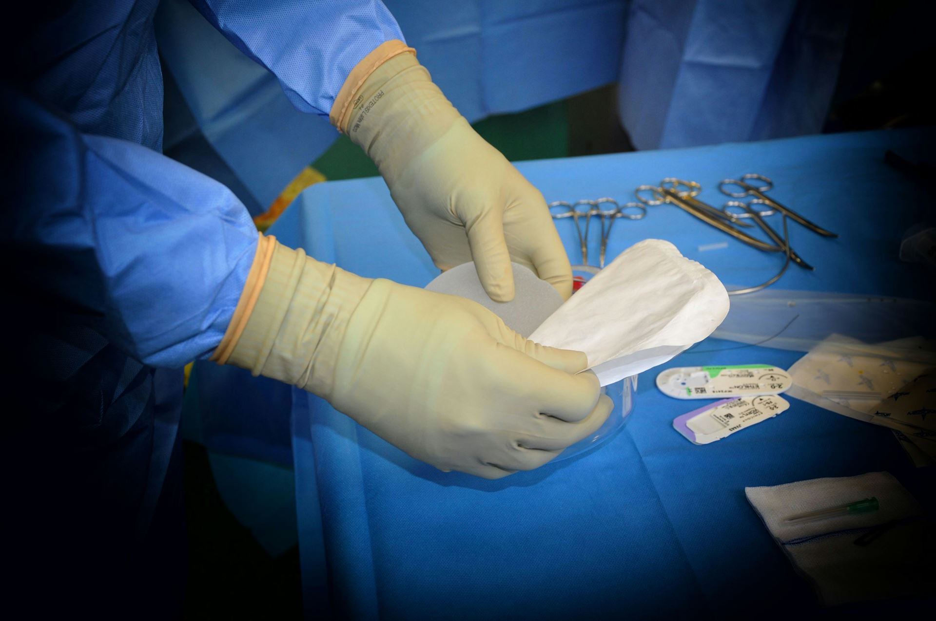 a clinician with surgical gloves on preparing a tray of instruments