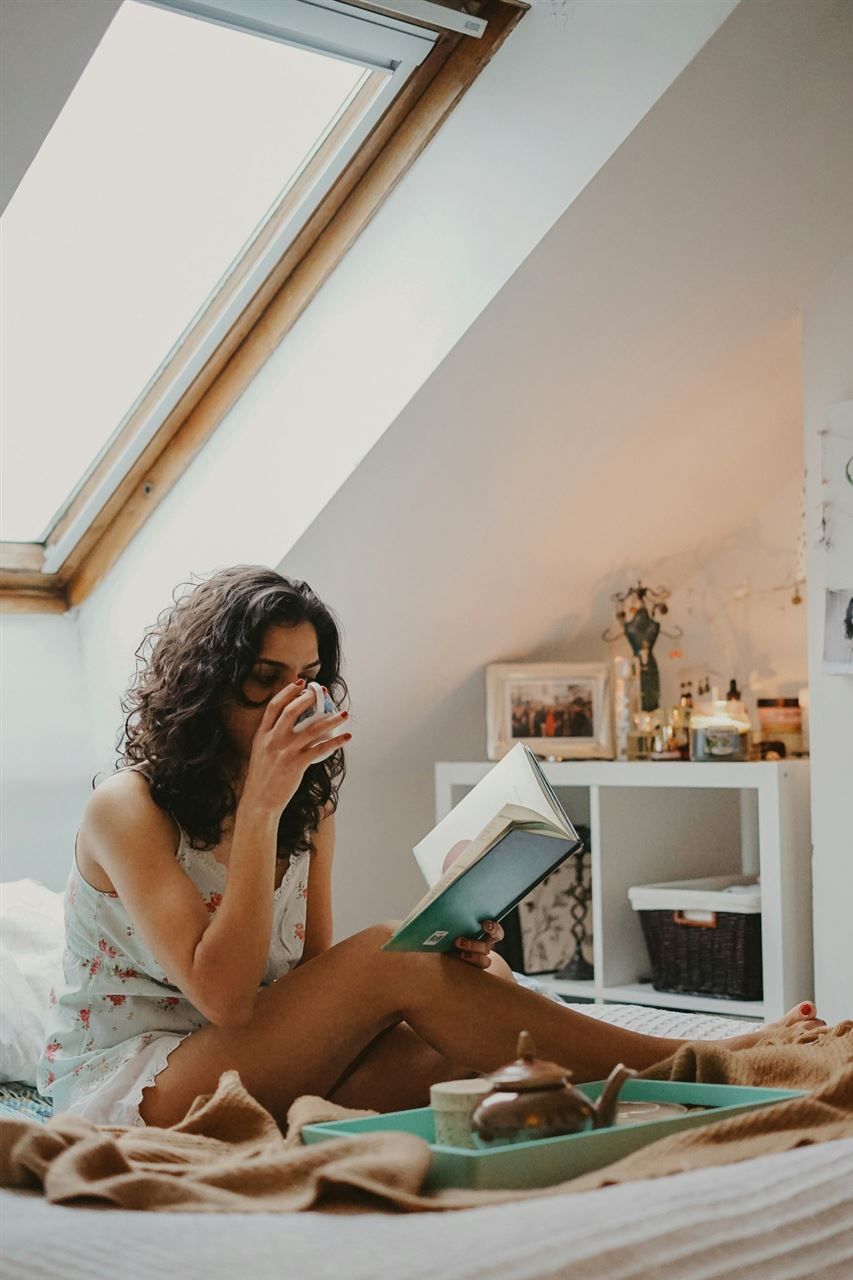 a woman reading a book and drinking tea