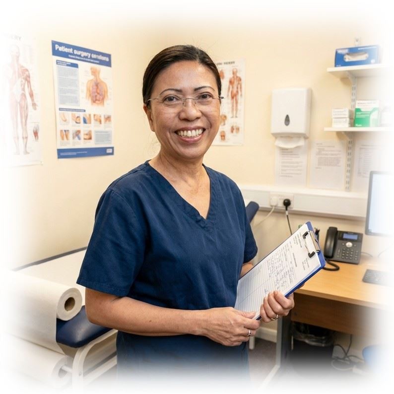 One of our nurses, Joy, in a clinical room holding a clipboard and smiling