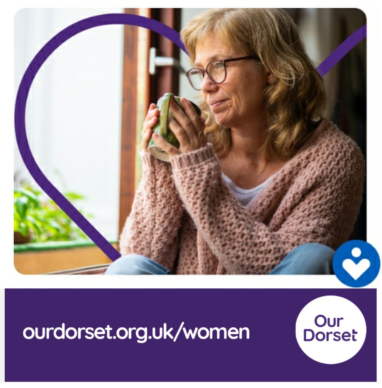 A middle aged woman holding a mug of hot coffee and looking out a window